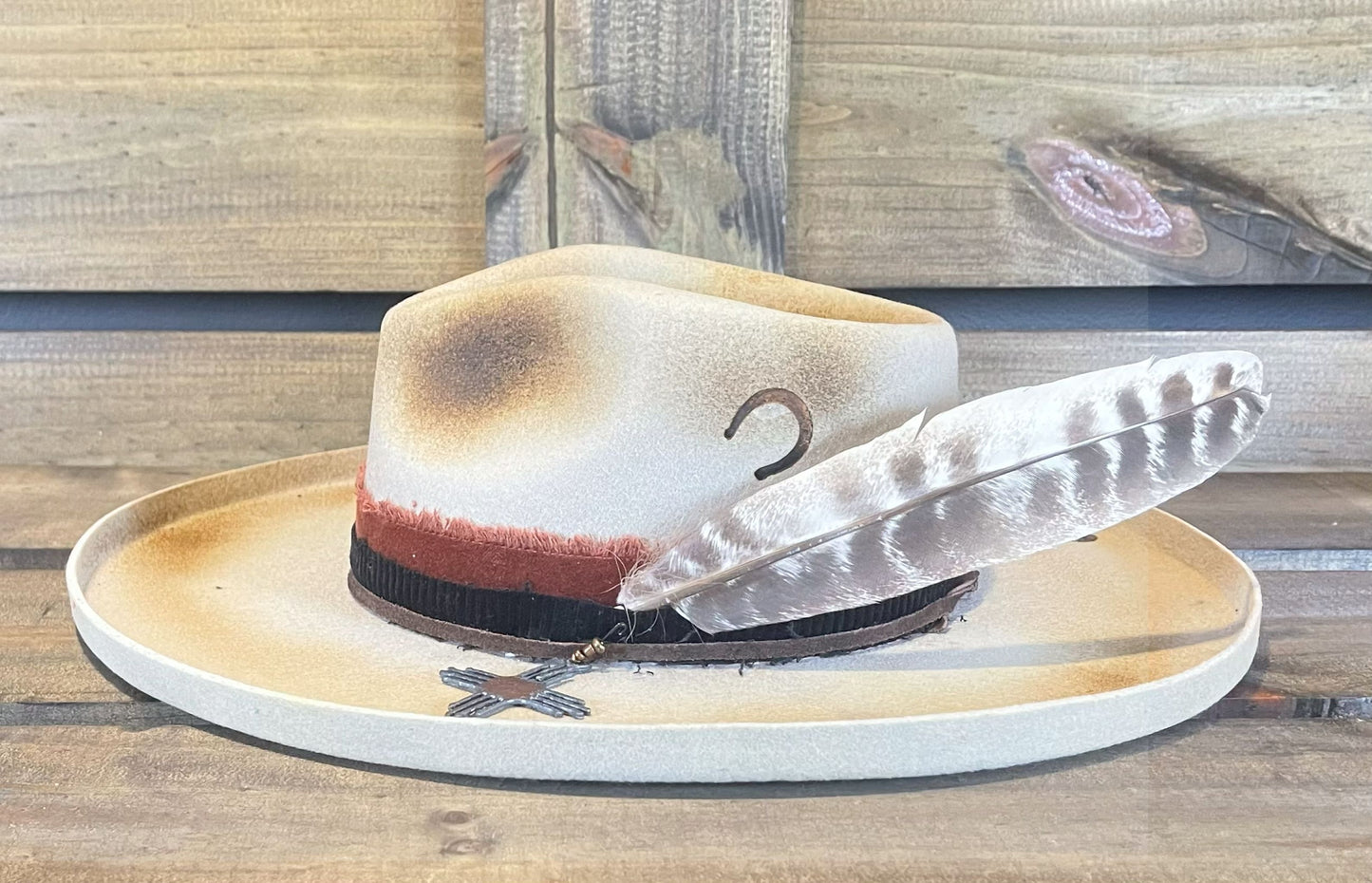 Peter Grimm hat with a wide pencil brim. Burned and styled with a large feather and a Zia charm.