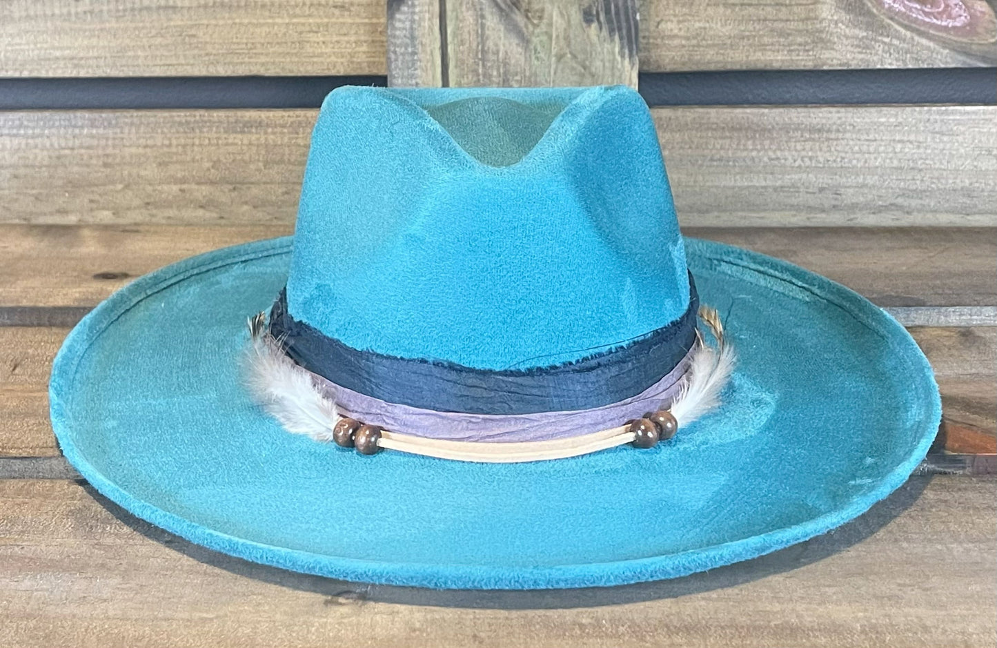 A Turquoise funky and fun vegan suede hat wrapped with recycled Sari silk and suede strings. Styled with Peacock feathers.