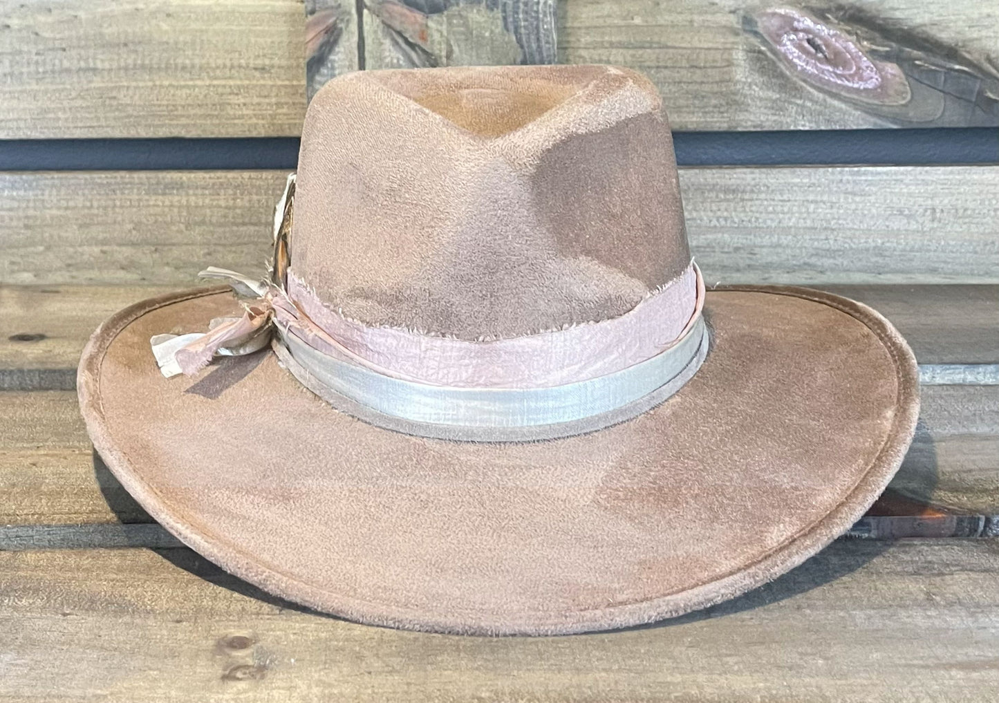 A taupe vegan suede hat with layered recycled silk bands. Styled with golden laced feathers.