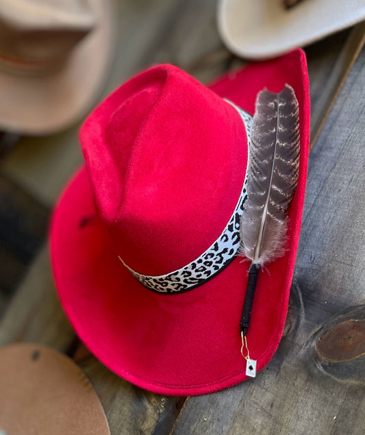 A red suede cowboy hat with a Leopard print band and styled with a large feather