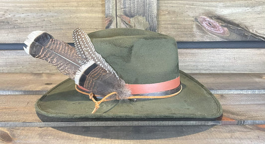 An olive green suede hat with leather bands and large feathers.