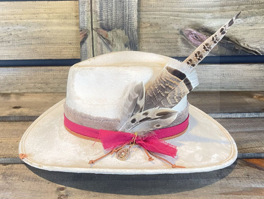 The Waller is a vegan suede hat burned and stitched. Layered with a frayed band and styled with a cluster of feathers.